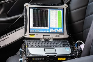 Testcomputer mit Messungen am Bildschirm steht auf dem Beifahrersitz