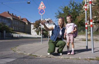 Ein Kind übt gemeinsam mit seiner Mama den Schulweg. Die beiden befinden sich an einer Kreuzung