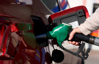 Eine Hand führt Zapfhahn an den Tankstutzen eines Fahrzeuges