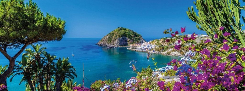 A view of Sant'Angelo in Ischia island in Italy: Tyrrhenian sea, bougaiunvillea glabra, rocks, water, umbrella, sand and old typical houses in the island in front of Naples in Campania region in a sunny day
