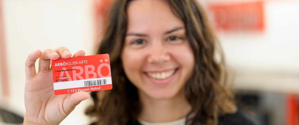 Junge, freundlich lächelnde Frau hält ihre ARBÖ-Klubkarte in die Kamera. 