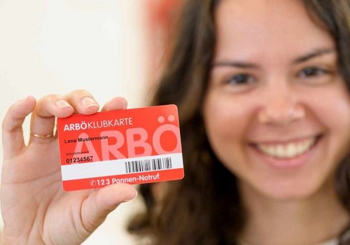 Junge, freundlich lächelnde Frau hält ihre ARBÖ-Klubkarte in die Kamera. 