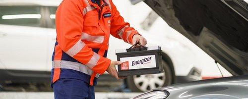 ARBÖ-Techniker hebt Batterie in den Motorraum.