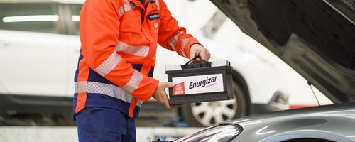 ARBÖ-Techniker hebt Batterie in den Motorraum.