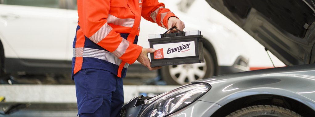 ARBÖ-Techniker hebt Batterie in den Motorraum.