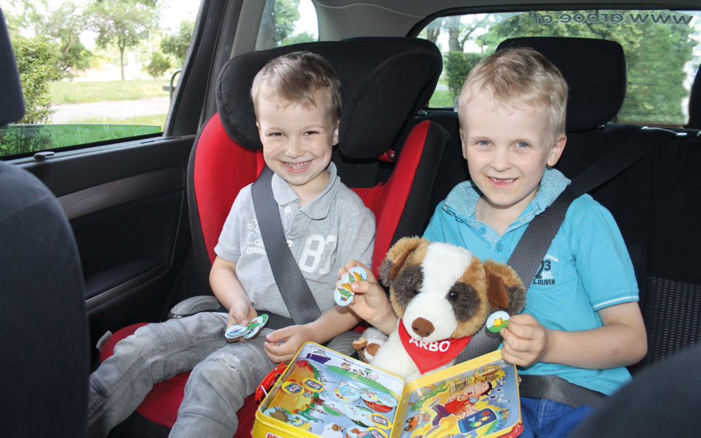 zwei Kinder im Auto mit Spielsachen 