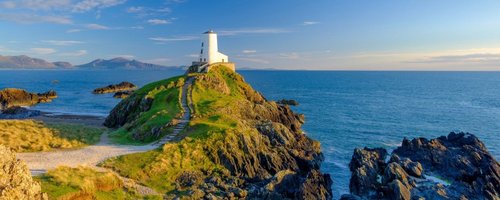 Leuchtturm in Wales an der Küste vor blauem Himmel, Anglesey