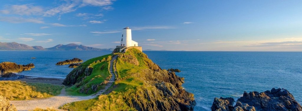 Leuchtturm in Wales an der Küste vor blauem Himmel, Anglesey