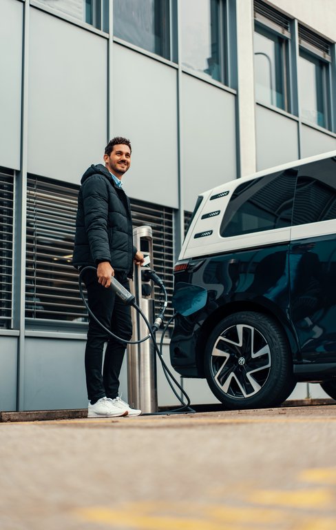 Mann lädt E-Auto auf