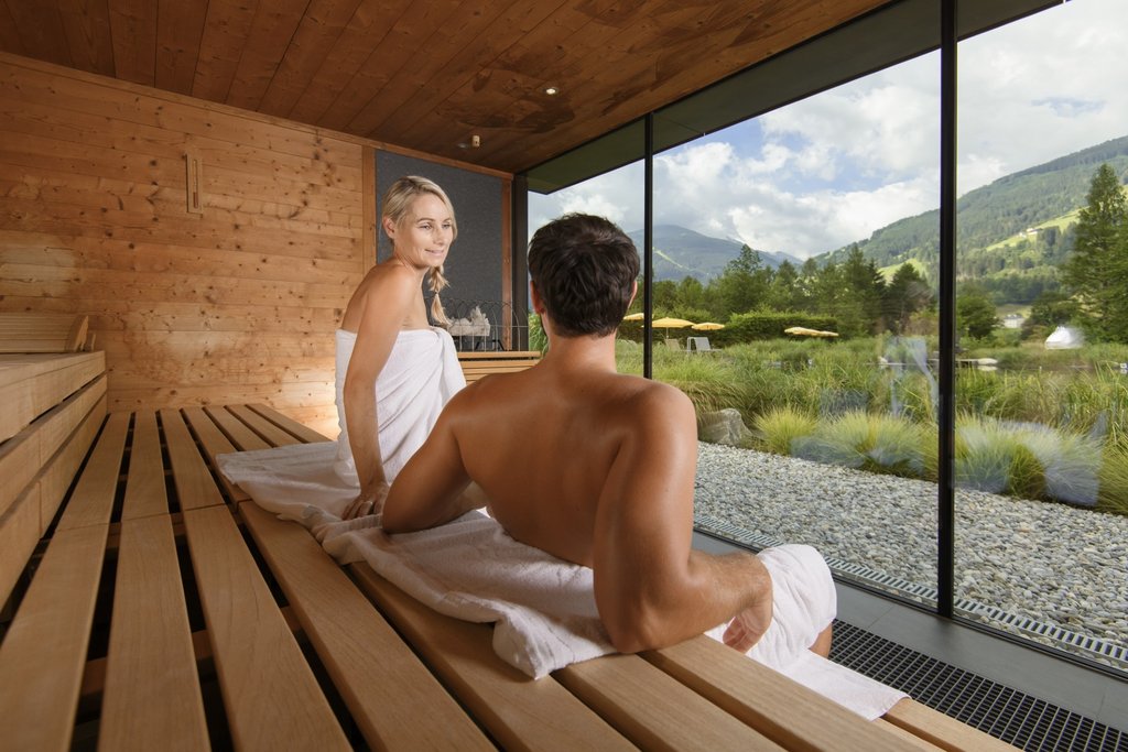 © Bergparadies Apartment & Studio Hotel Eine Frau und ein Mann sitzen in einer Sauna