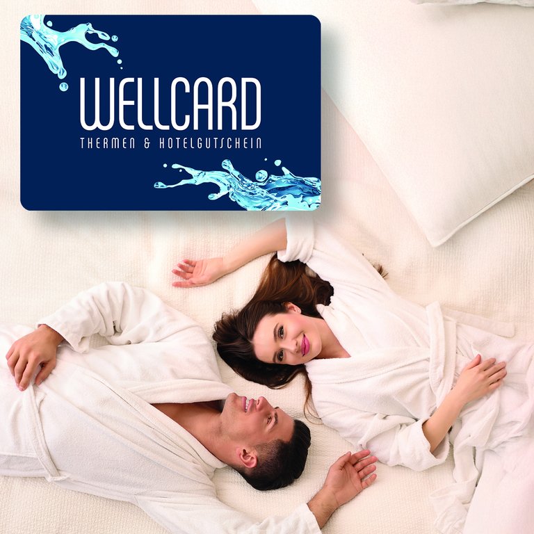 Pärchen im Bademantel auf einem Bett liegend, WellCard Gutscheinkarte darüber