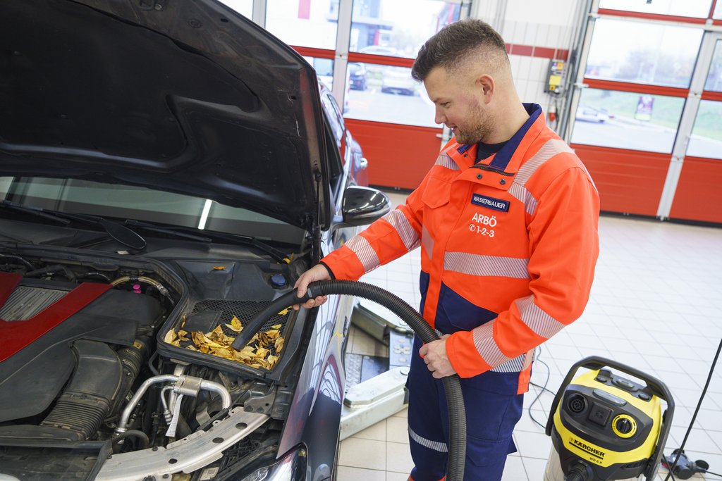 Techniker befreit Motorraum von Laub